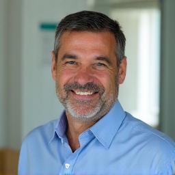 Carlos Martin, director hospital privado, sonriente con hospital moderno